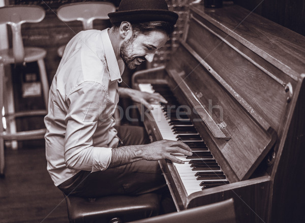 Trendy man with stylish hat and beard trying playing vintage old Stock photo © DisobeyArt