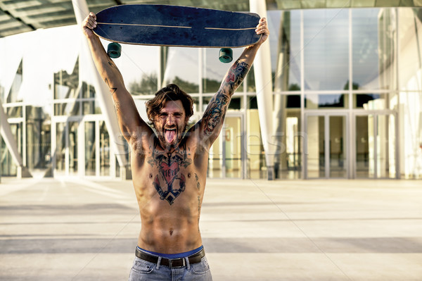 Bearded skater with tattoos holding longboard outside of confere Stock photo © DisobeyArt