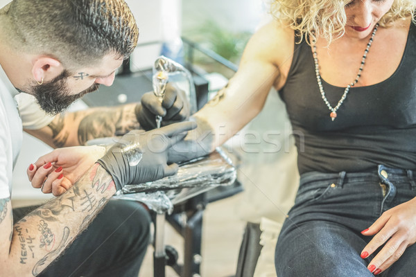Professional bearded tattoo artist making tattoo in his own ink  Stock photo © DisobeyArt
