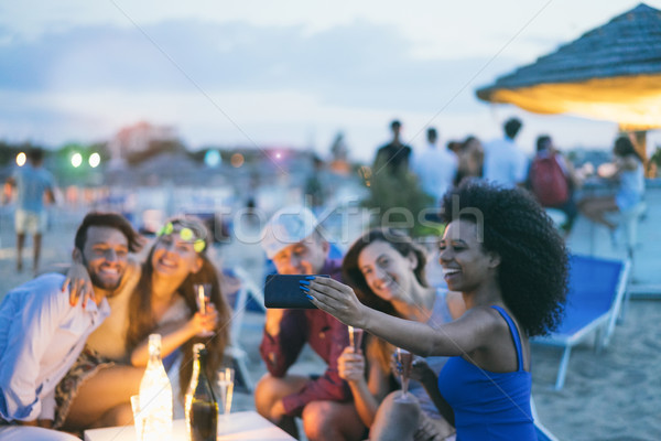 Happy friends taking selfie with smartphone at beach party outdo Stock photo © DisobeyArt