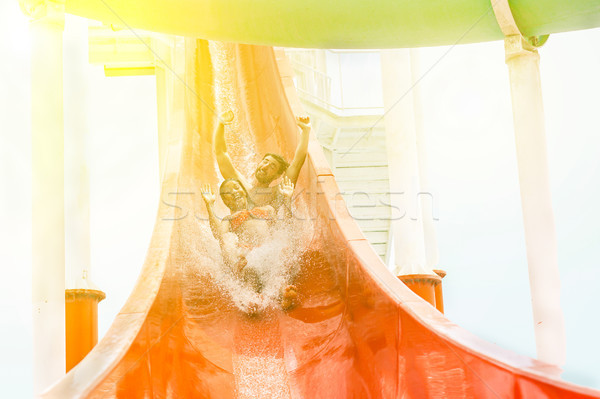 Young handsome couple splashing into a waterslide in aqua park f Stock photo © DisobeyArt