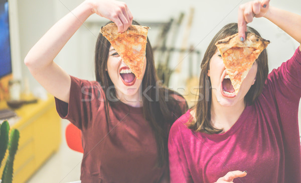 Two female friends holding pizza slices in front of their faces  Stock photo © DisobeyArt