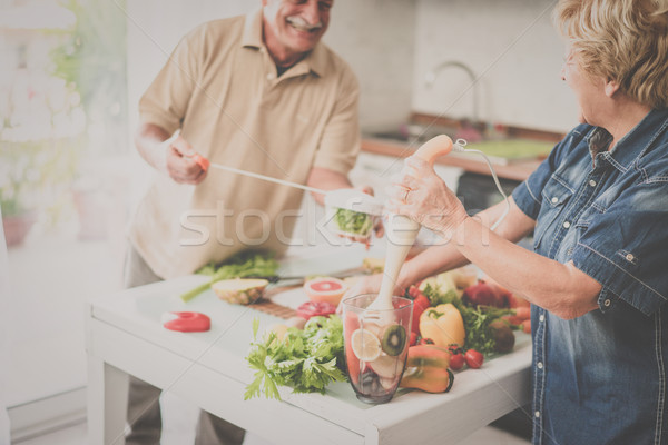 Senior couple cooking healthy vegan meal with fruits and vegetab Stock photo © DisobeyArt