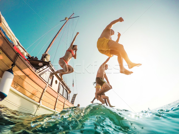 Happy friends diving from sailing boat into the sea - Young peop Stock photo © DisobeyArt