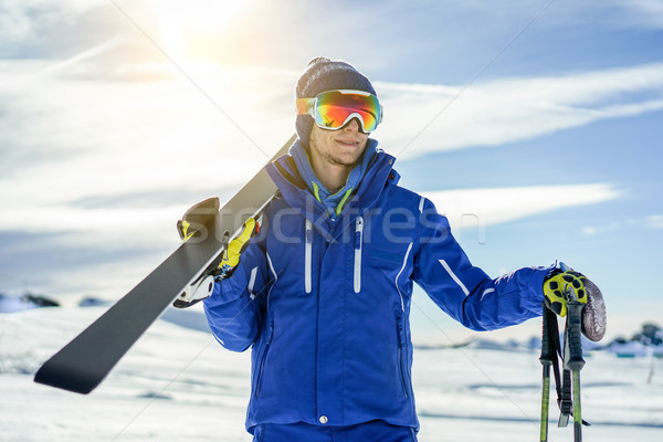 Stock photo: Skier watching the horizon holding skiing equipment with sun bac