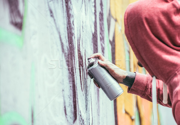 Tattoo graffiti writer painting with color spray his dark pictur Stock photo © DisobeyArt