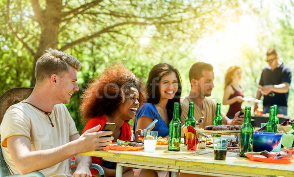 Stock photo: Happy friends toasting beer and having barbecue outdoor with bac