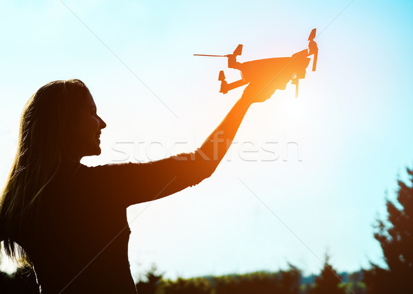 Silhouette of young woman using drone at sunset for photos and v Stock photo © DisobeyArt