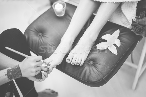 Tattoo beauty shop spa worker painting feet nails to young woman Stock photo © DisobeyArt