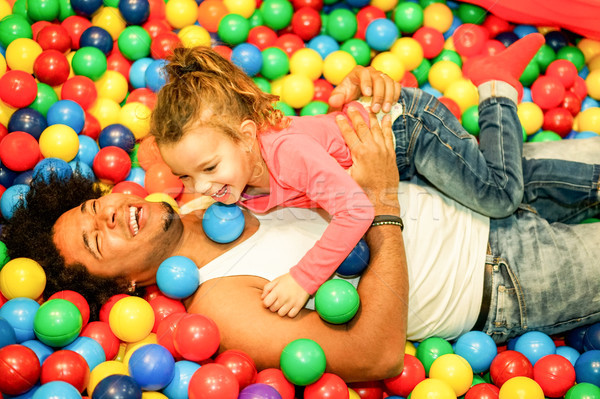 Stock photo: Young father playing with his daughter inside ball pit swimming 