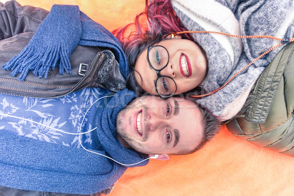 Happy couple lying down holding heads together looking up at the Stock photo © DisobeyArt
