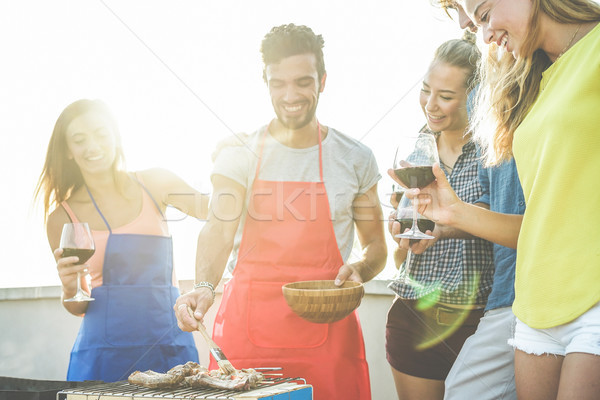 Happy students cooking and drinking wine at rooftop barbecue din Stock photo © DisobeyArt