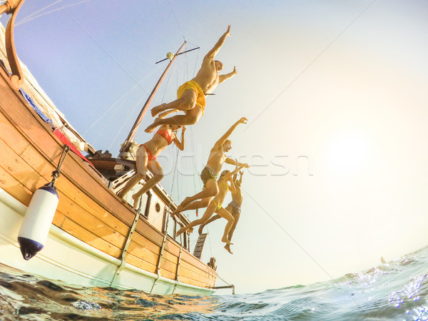 Happy friends diving from sailing boat into the sea - Young peop Stock photo © DisobeyArt