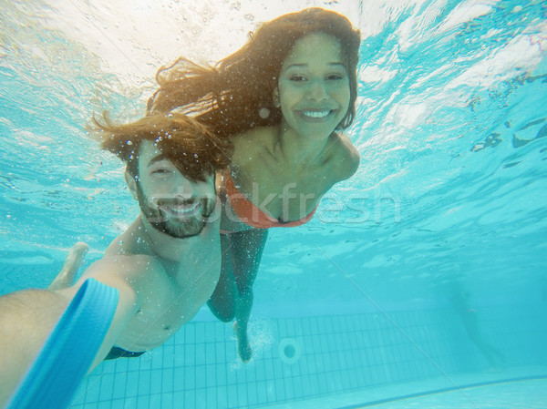 Happy couple taking selfie under the water in swimming pool reso Stock photo © DisobeyArt