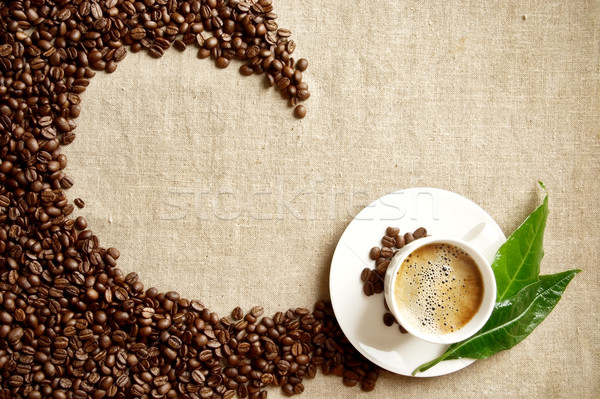 Frothy coffee cup, beans,leaf twisted in swirl on flax  Stock photo © dla4