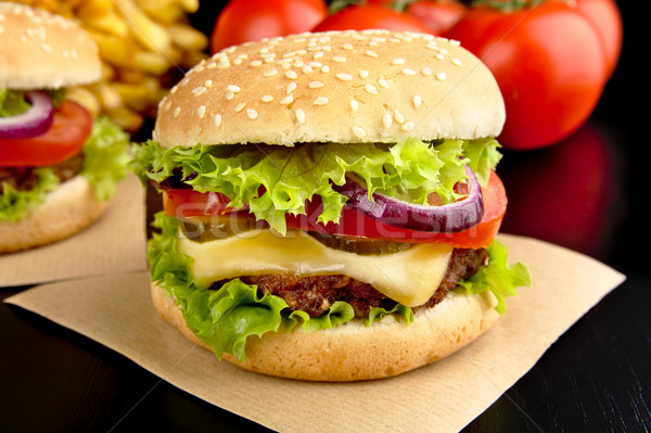 Big cheeseburgers on paper on black Stock photo © dla4