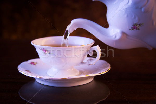 Old-style pouring tea to cup on black background Stock photo © dla4