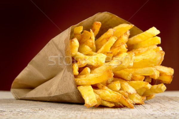 French fries in the paper bag on burned background on wooden table Stock photo © dla4