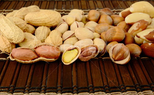 Stock photo: Nuts in line-peanuts,walnuts,pistachios,brasil nuts on brown mat