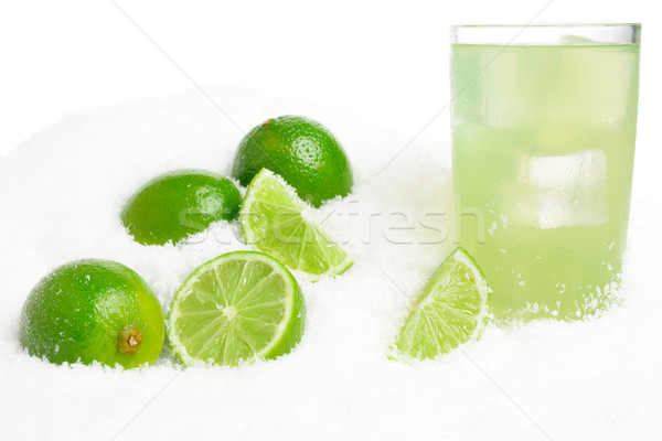Glass of lime juice with ice cubes,limes on snow on white Stock photo © dla4