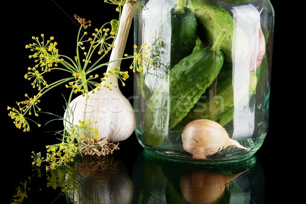 Cropped shot of cucumbers in jar preparate for canning isolated on black Stock photo © dla4