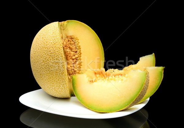 Melon galia with slices on plate isolated black in studio Stock photo © dla4