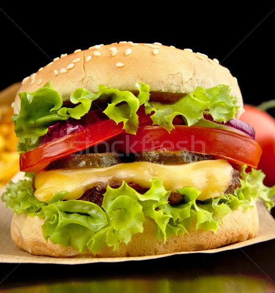 Closeup macro shot of big cheeseburger on paper on black Stock photo © dla4