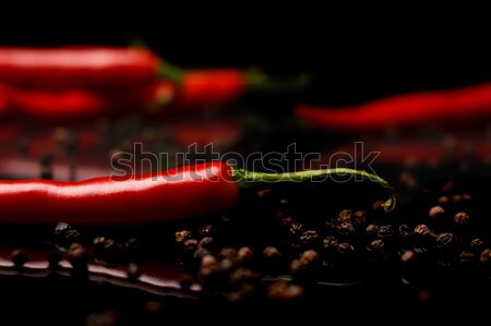 Studio shot of chilli peppers and black pepper on black Stock photo © dla4