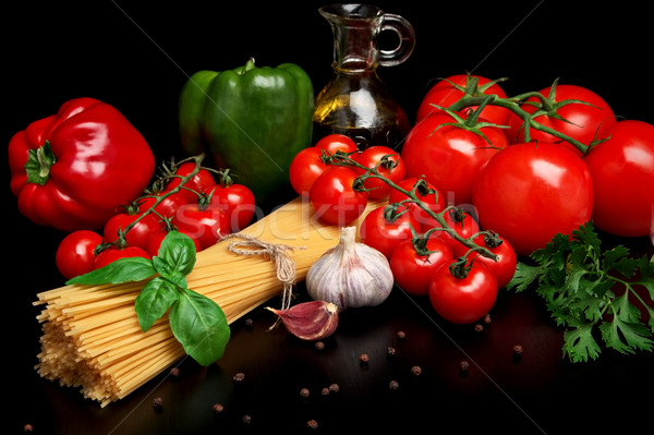 Pasta raw isolated on black with tomatoes,olive oil,garlic verti Stock photo © dla4