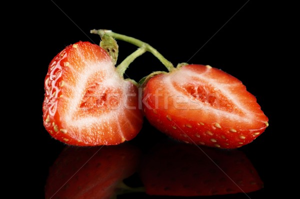 Halved strawberry isolated on black with green stalk Stock photo © dla4