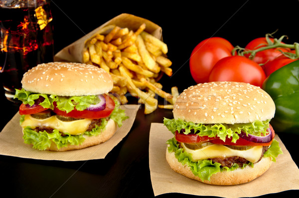 Big cheeseburgers on paper,french fries and glass of cola on black Stock photo © dla4