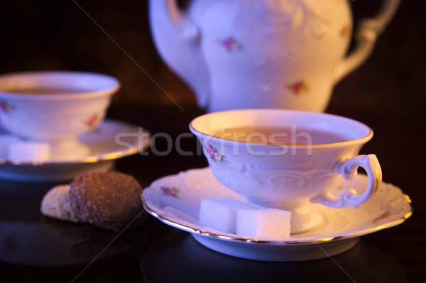 Old-style kettle with two cups of tea with cookies on black Stock photo © dla4