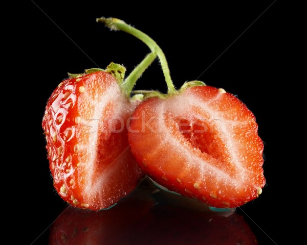 Halved strawberry isolated on black with green stalk Stock photo © dla4