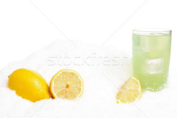 Glass of lime juice with ice cubes,lemons on snow on white Stock photo © dla4