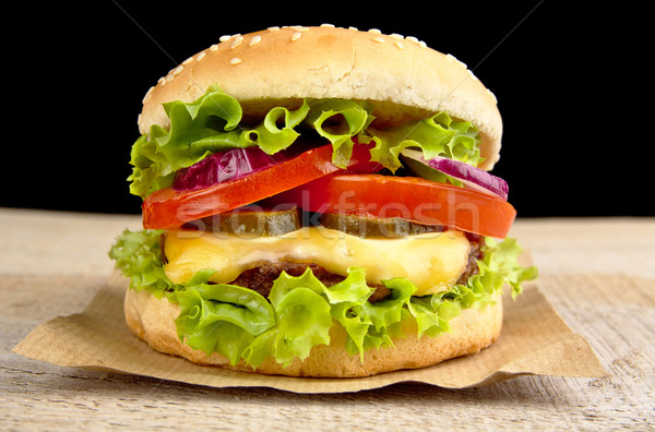 Big cheeseburger on wooden board on black background Stock photo © dla4