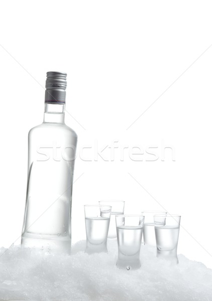 Bottle of vodka with glasses standing on ice on white background Stock photo © dla4