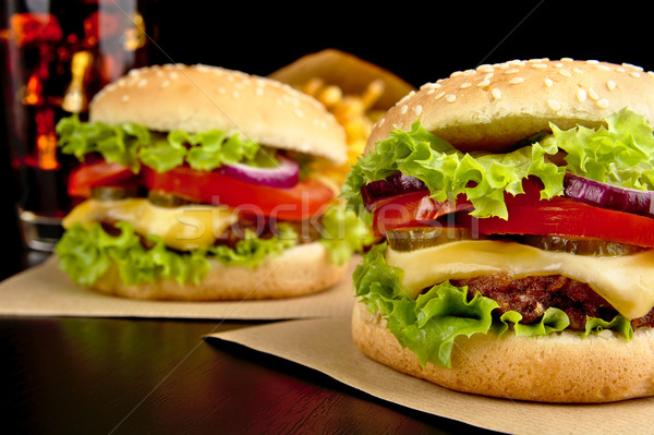 Cheeseburgers,french fries and cola on wooden desk on black Stock photo © dla4