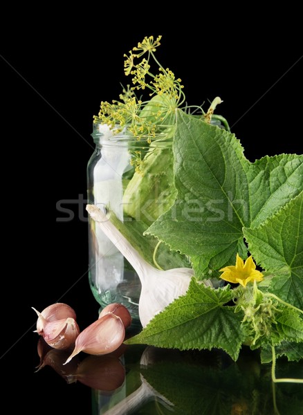 Cropped shot of cucumbers in jar preparate for canning isolated on black Stock photo © dla4