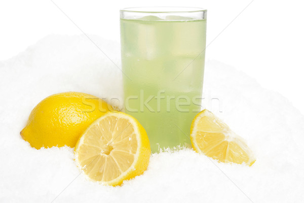 Glass of lime juice with ice cubes,lemons on snow on white Stock photo © dla4