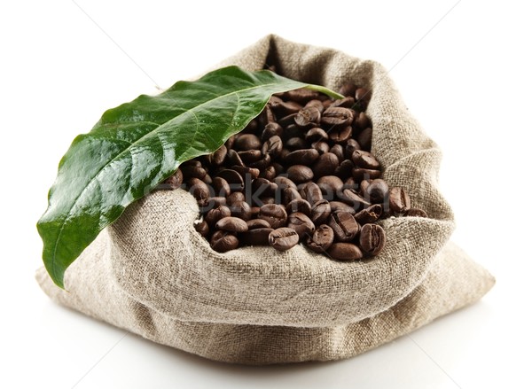 Sack full of coffee beans on white with green leaf Stock photo © dla4