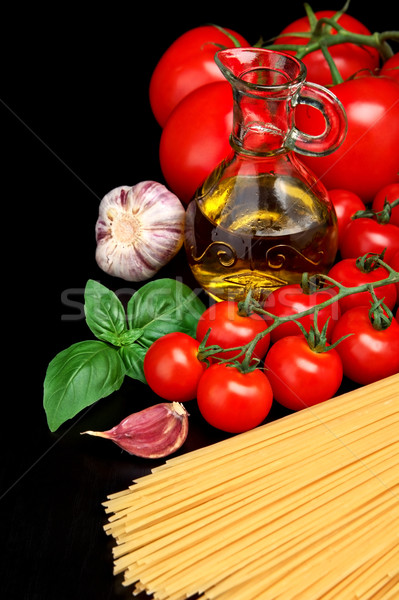 Pasta raw isolated on black with tomatoes,olive oil,garlic verti Stock photo © dla4