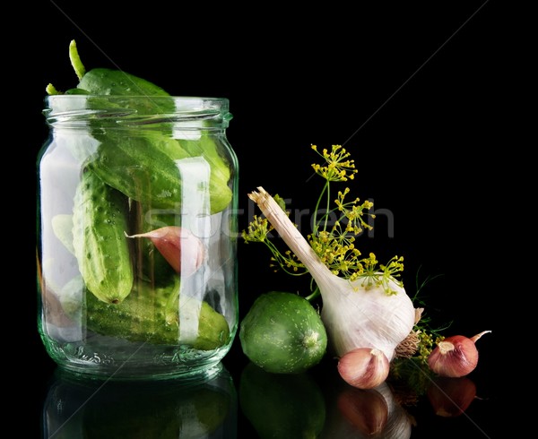 Cucumbers in jar preparate for pickling on black Stock photo © dla4