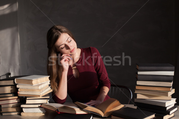 the girl sitting at the table reading a lot of books Stock photo © dmitriisimakov