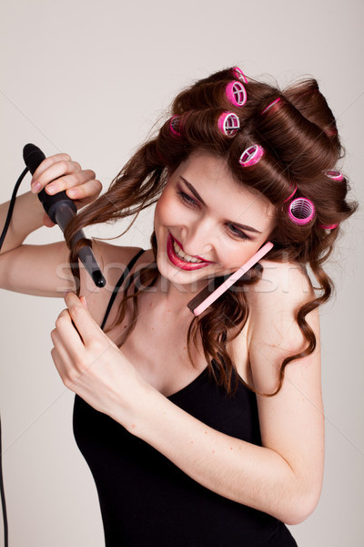 Stock photo: girl with hair curlers talking on the phone and makes the hairstyle