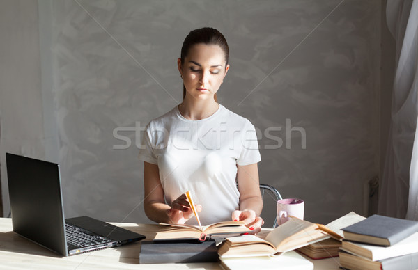 girl is preparing for the exam reading book works at the computer Stock photo © dmitriisimakov