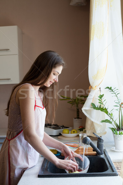 Stock photo: girl housewife washes dirty dishes in the kitchen