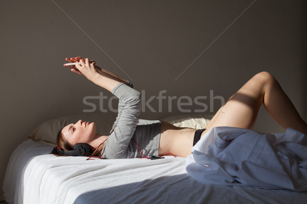 girl with big headphones and a smartphone rests on the bed Stock photo © dmitriisimakov