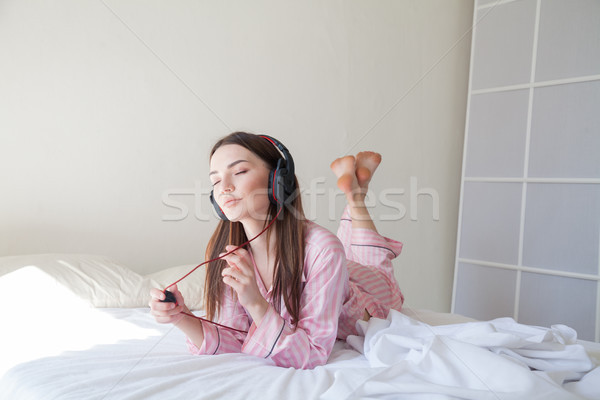 Stockfoto: Brunette · roze · pyjama · luisteren · naar · muziek · hoofdtelefoon · bed