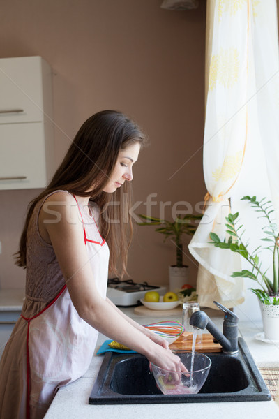 Stock photo: girl housewife washes dirty dishes in the kitchen