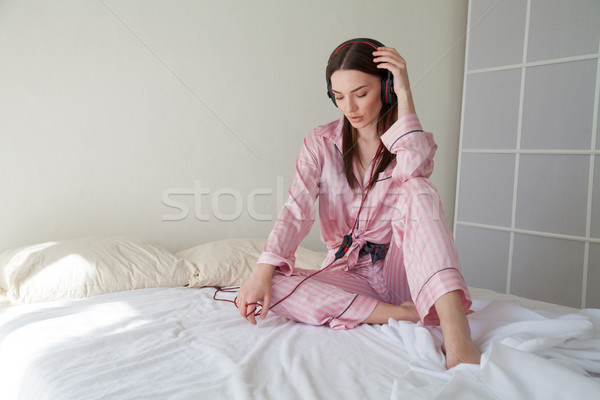 brunette woman in pajamas listening to music lies in bed Stock photo © dmitriisimakov